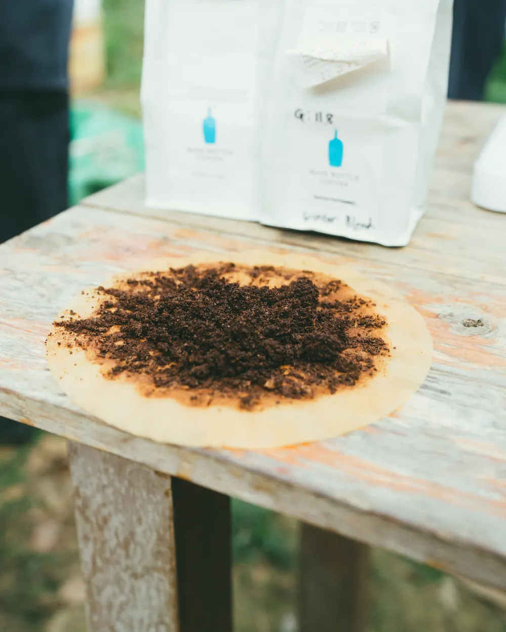 Used coffee grounds on a filter beside bags of beans